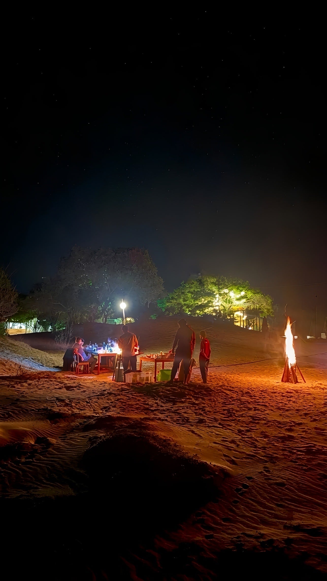 A fire and a table set on the sand at Arugam Bay after dark